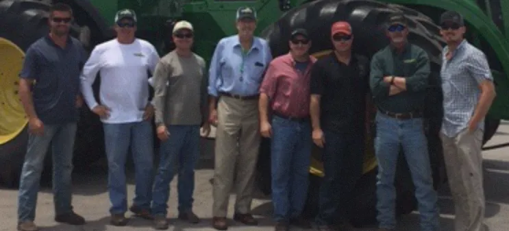 The management team in front of a green tractor: Gary Noland, Andy Ballard, John L. Hundley, John S. Hundley, Tom Perryman, Eric Hopkins, and Artie Garza